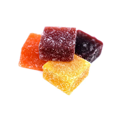 Assorted sugar-coated chewy fruit candy squares on white background